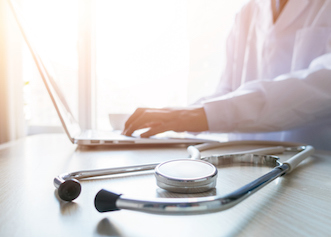 Doctor typing information on the computer in office